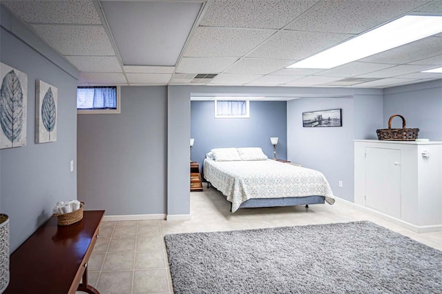 bedroom with multiple windows, light tile patterned flooring, and a drop ceiling