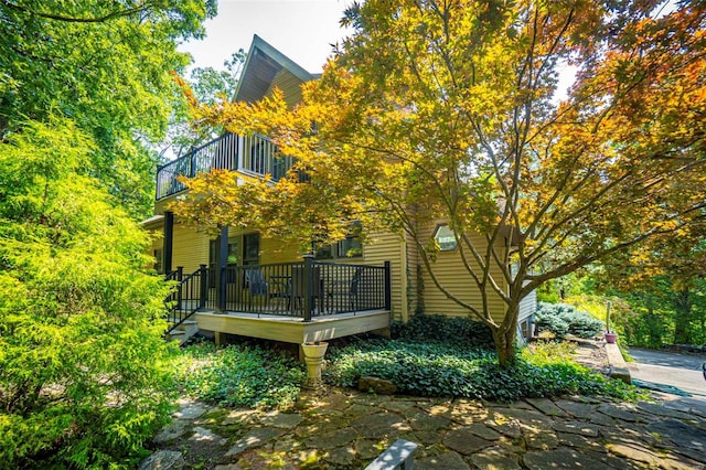 rear view of property with a balcony and a wooden deck