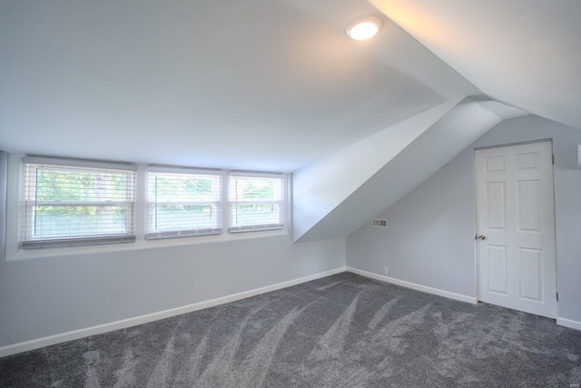 bonus room with vaulted ceiling and dark carpet