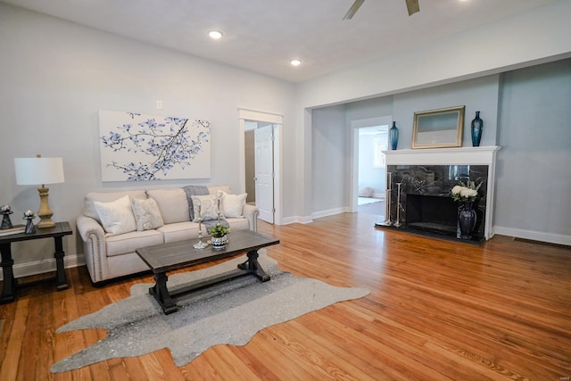 living room featuring ceiling fan, hardwood / wood-style floors, and a fireplace