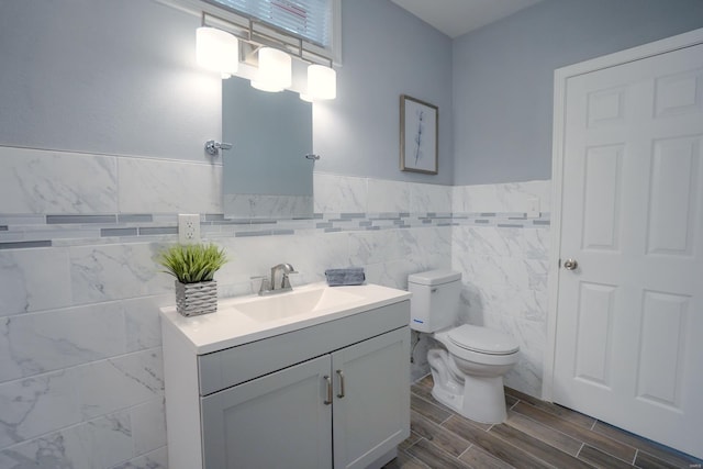 bathroom with vanity, toilet, and tile walls