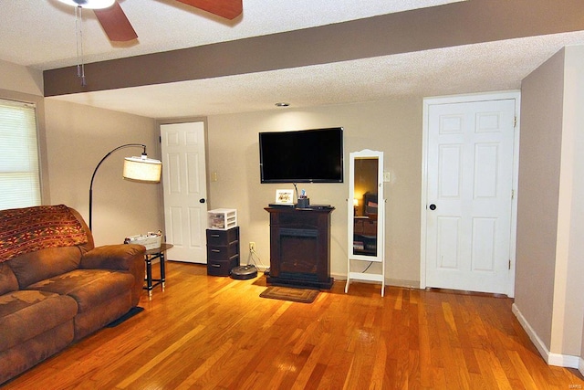 living room with hardwood / wood-style flooring, ceiling fan, and a textured ceiling