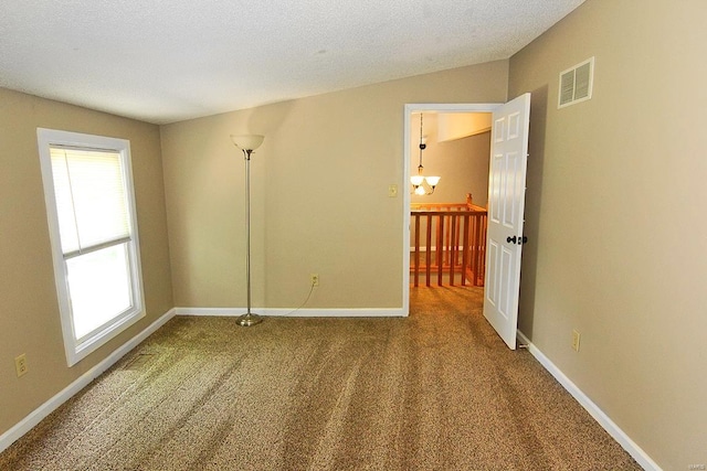 carpeted empty room with plenty of natural light and a textured ceiling