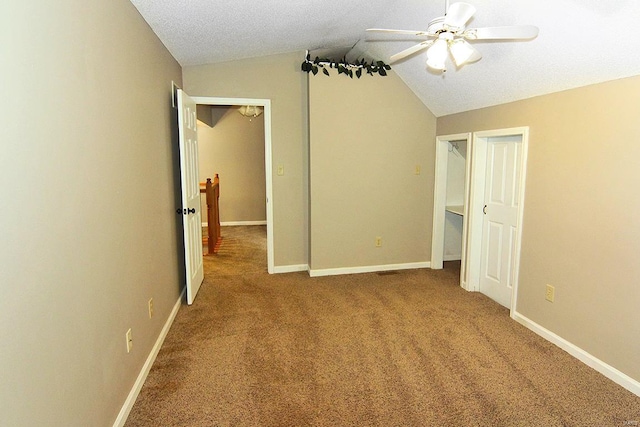 unfurnished bedroom featuring ceiling fan, carpet flooring, vaulted ceiling, and a textured ceiling