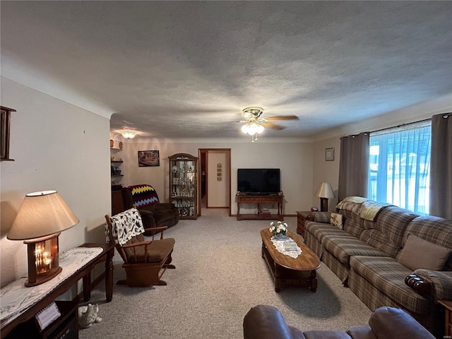 carpeted living room with ceiling fan and a textured ceiling