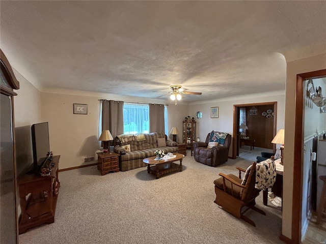 carpeted living room with ceiling fan and a textured ceiling