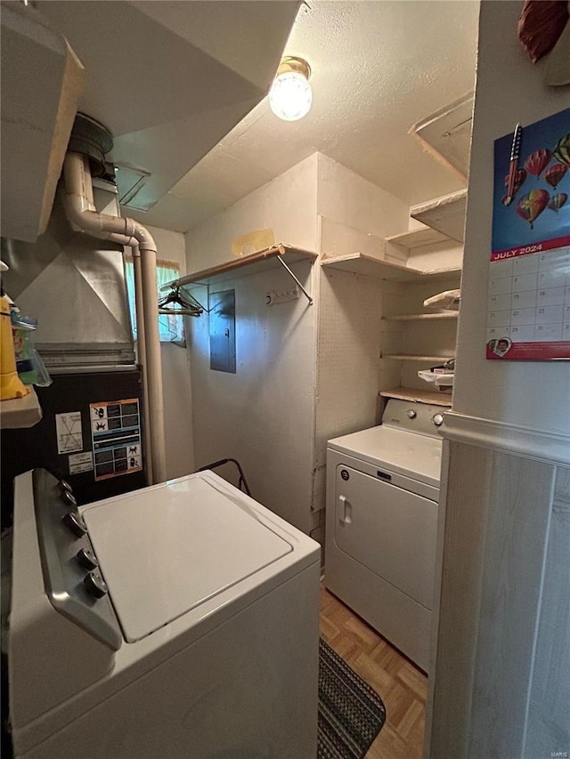 clothes washing area with parquet flooring, electric panel, and washer and clothes dryer