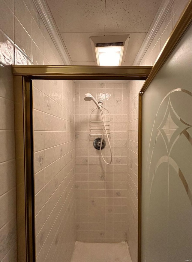 bathroom with a shower with door and crown molding