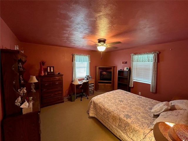 carpeted bedroom with ceiling fan and a textured ceiling