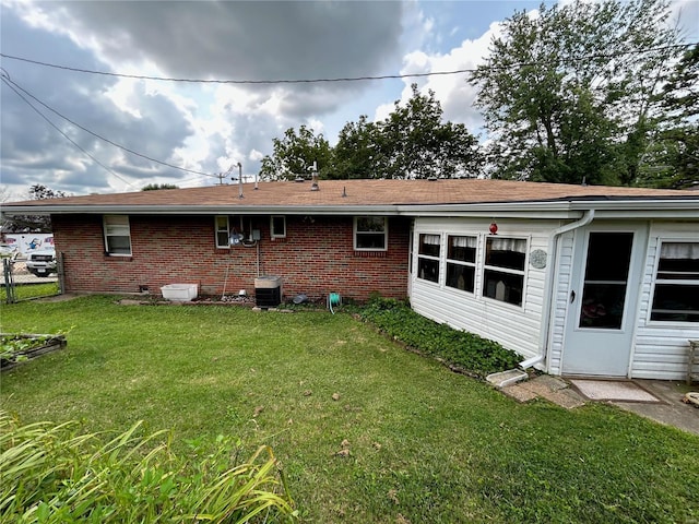 rear view of house with cooling unit and a lawn