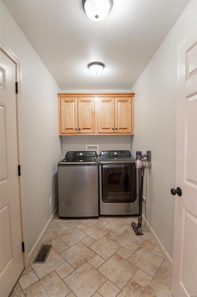 washroom with cabinets, washing machine and clothes dryer, and light tile patterned floors