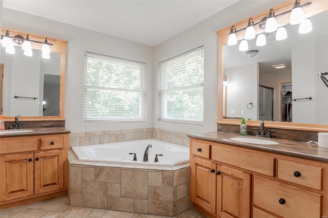 bathroom featuring a relaxing tiled tub, double vanity, and tile patterned floors