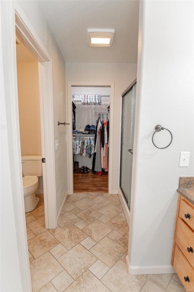 bathroom featuring wood-type flooring, a shower with door, toilet, and vanity