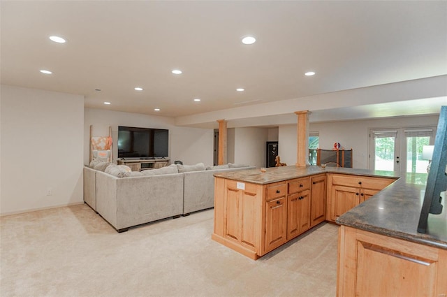 kitchen featuring dark stone counters, light carpet, french doors, ornate columns, and kitchen peninsula