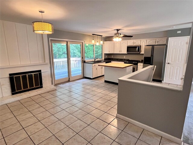 kitchen featuring ceiling fan, pendant lighting, white cabinets, a kitchen island, and appliances with stainless steel finishes