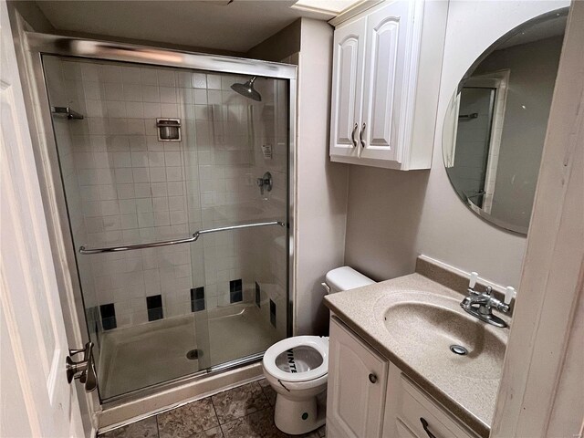 bathroom featuring tile patterned floors, a shower with shower door, vanity, and toilet