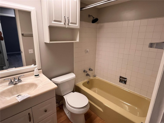 full bathroom with tiled shower / bath, hardwood / wood-style flooring, vanity, and toilet