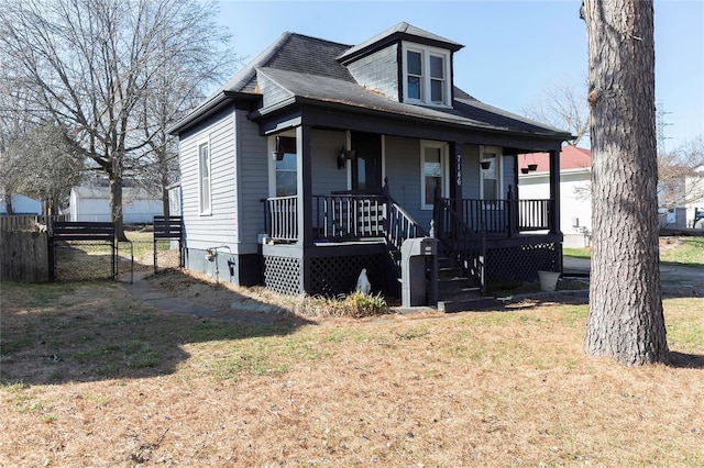 bungalow-style house featuring a porch, a gate, fence, and a front lawn