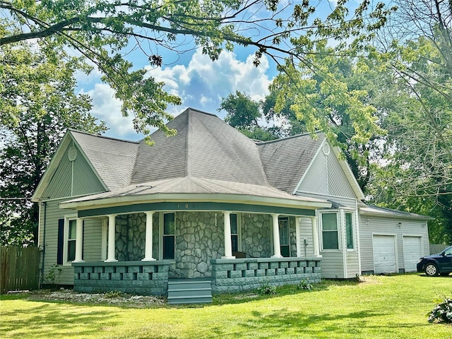 view of front of house featuring covered porch, a garage, and a front lawn