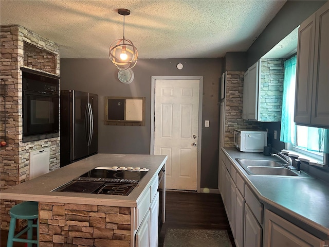 kitchen with sink, decorative light fixtures, gas cooktop, dark hardwood / wood-style floors, and stainless steel refrigerator