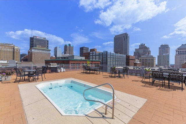 view of swimming pool featuring a city view, a hot tub, and area for grilling