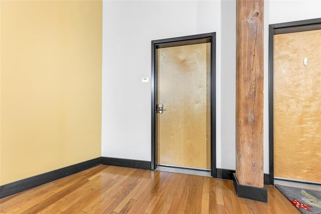 spare room featuring wood-type flooring and baseboards