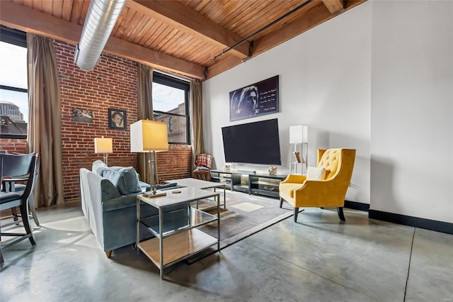 living area featuring a wealth of natural light, baseboards, concrete floors, and brick wall