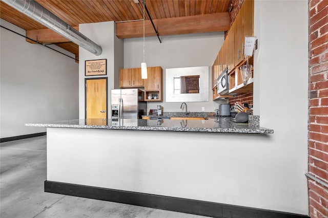 kitchen featuring appliances with stainless steel finishes, stone countertops, beamed ceiling, and brick wall