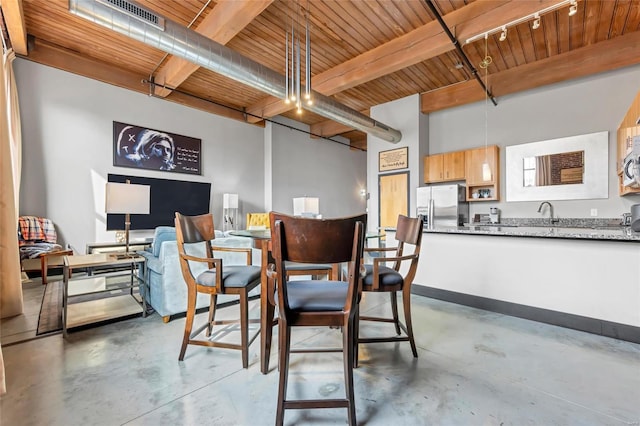 dining space featuring concrete flooring, wood ceiling, rail lighting, and beam ceiling