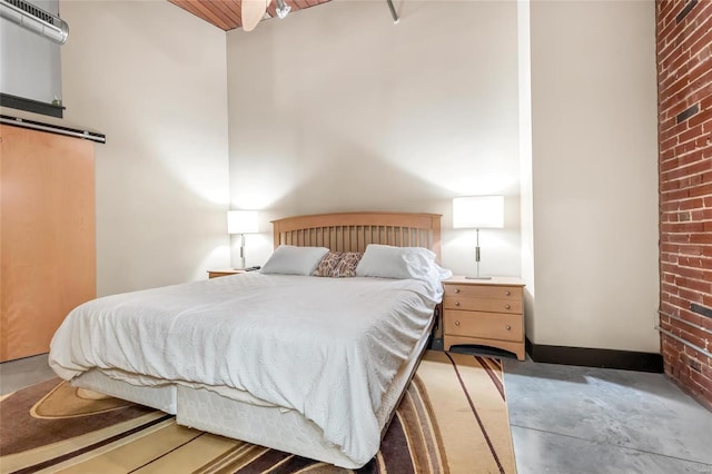 bedroom featuring concrete flooring, baseboards, and a barn door