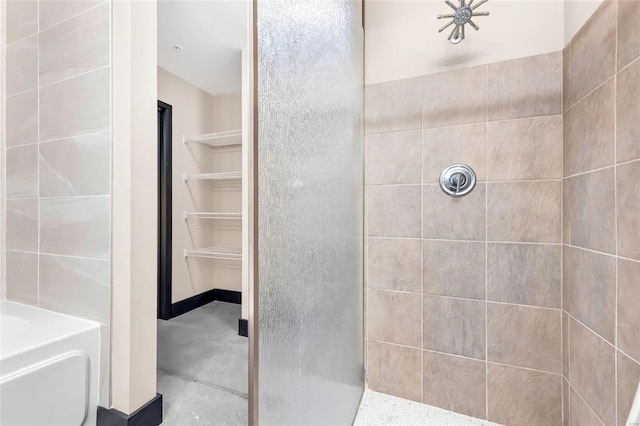 full bathroom featuring a washtub, a tile shower, and a spacious closet