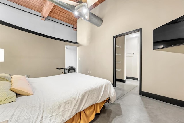 bedroom featuring concrete flooring, a towering ceiling, and baseboards