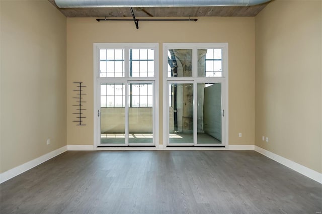 empty room featuring hardwood / wood-style flooring, plenty of natural light, and a high ceiling