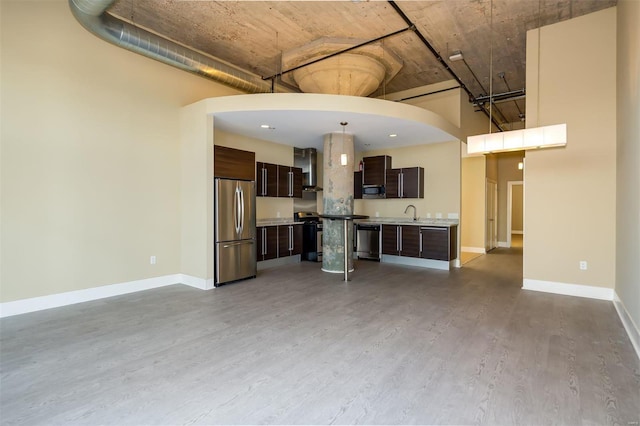 unfurnished living room with a sink, baseboards, a high ceiling, and light wood-style flooring