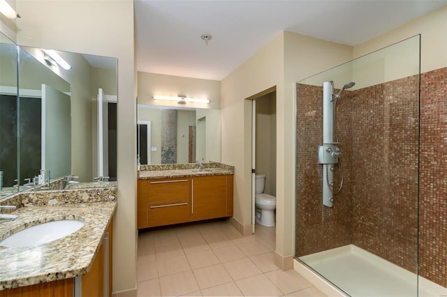 bathroom featuring tile patterned flooring, vanity, a tile shower, and toilet