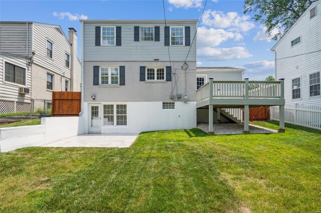 rear view of house featuring a deck, a patio, and a lawn