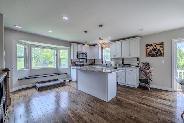 kitchen featuring appliances with stainless steel finishes, white cabinetry, hanging light fixtures, and dark hardwood / wood-style floors