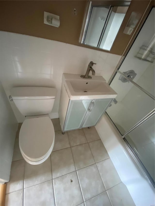 full bathroom featuring tile walls, shower / bath combination with glass door, tile patterned flooring, and toilet