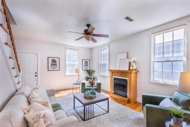 living room featuring a wealth of natural light, light wood-type flooring, and ceiling fan