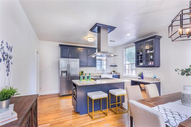 kitchen featuring stainless steel appliances, light hardwood / wood-style floors, a kitchen island, and island exhaust hood