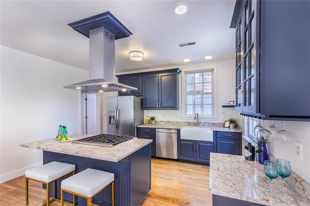 kitchen featuring stainless steel appliances, sink, light hardwood / wood-style flooring, island range hood, and a kitchen breakfast bar