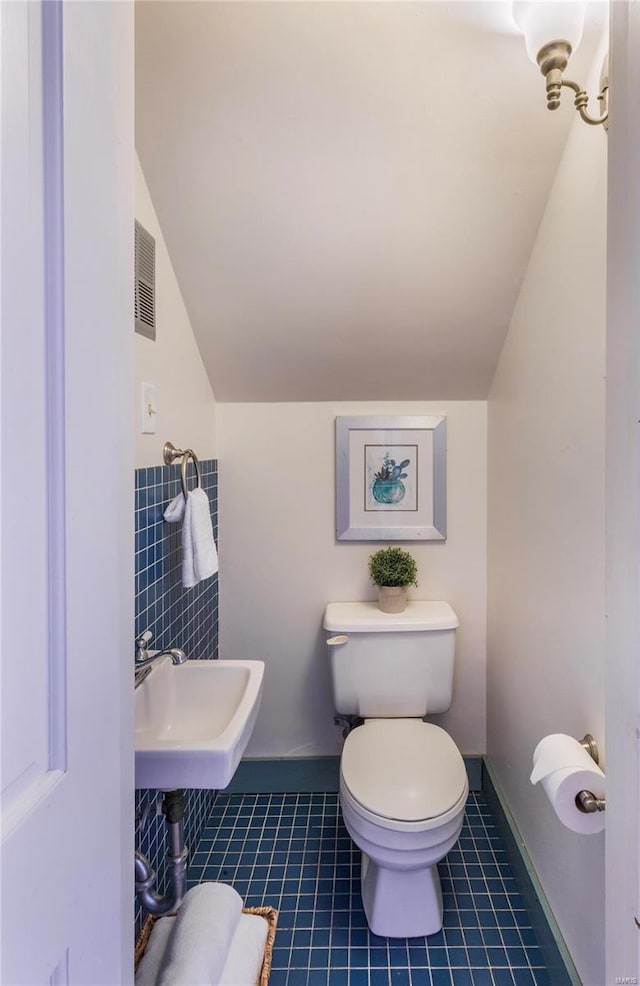 bathroom with tile patterned flooring, lofted ceiling, toilet, and sink