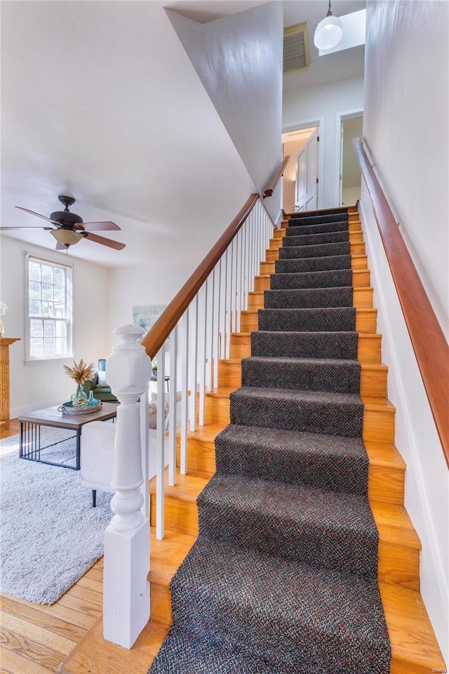 staircase featuring light wood-type flooring and ceiling fan