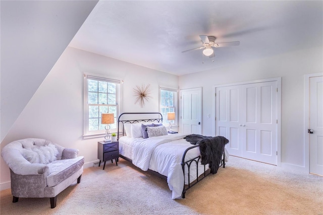 bedroom with multiple closets, light carpet, and ceiling fan