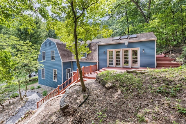 back of property with a wooden deck and french doors