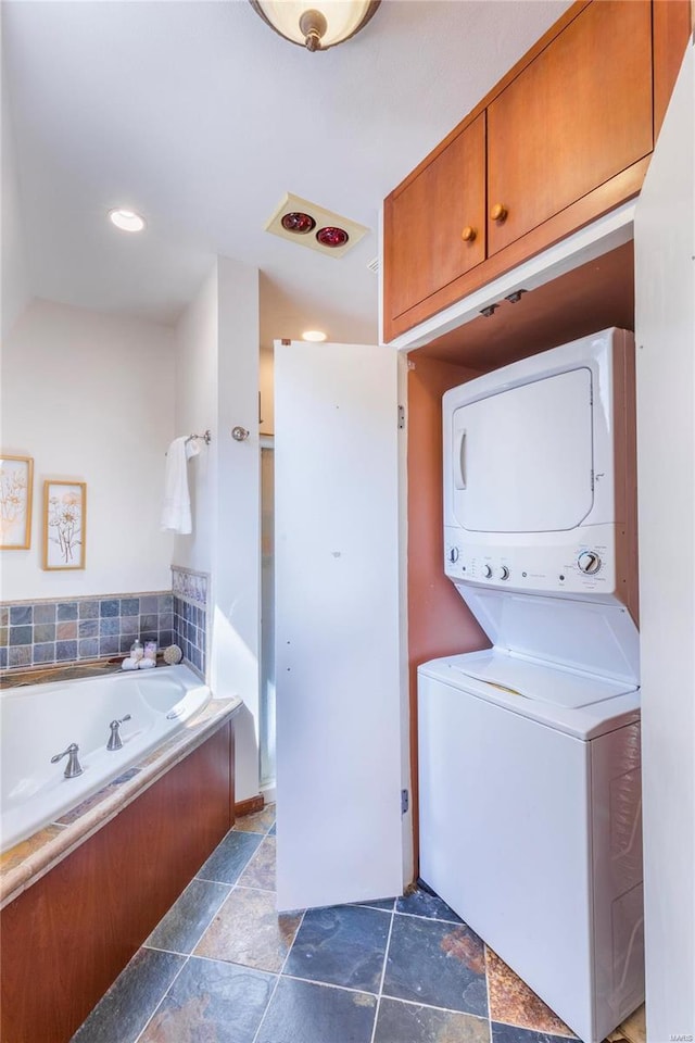 laundry area featuring dark tile patterned floors and stacked washer and dryer