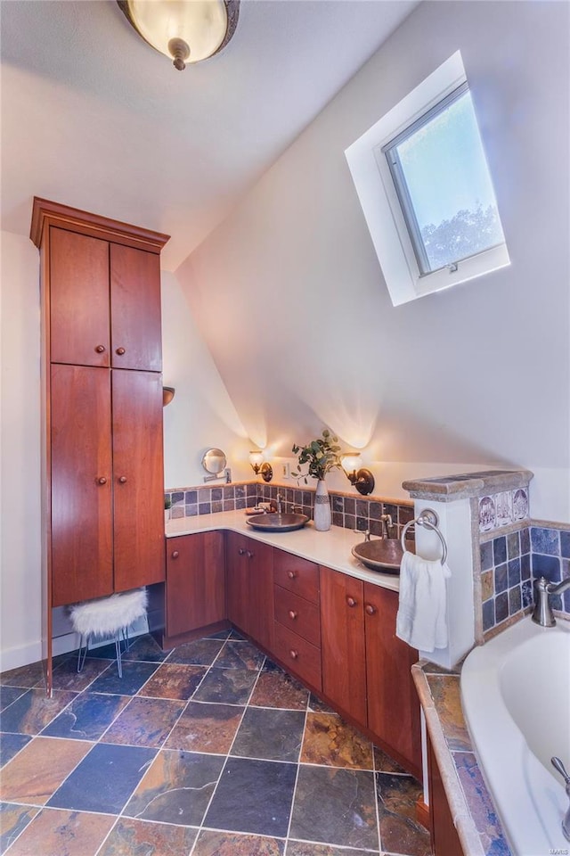 bathroom featuring tile patterned floors, a bath, double sink vanity, and vaulted ceiling with skylight