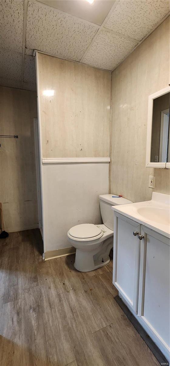 bathroom featuring a drop ceiling, hardwood / wood-style floors, vanity, and toilet