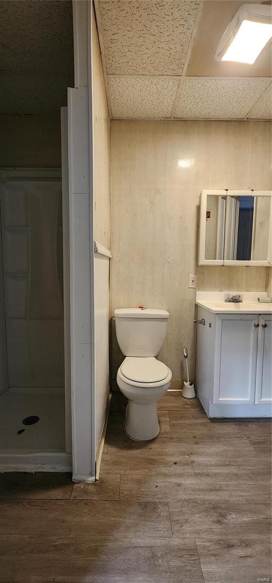 bathroom with vanity, hardwood / wood-style floors, toilet, a shower, and a drop ceiling