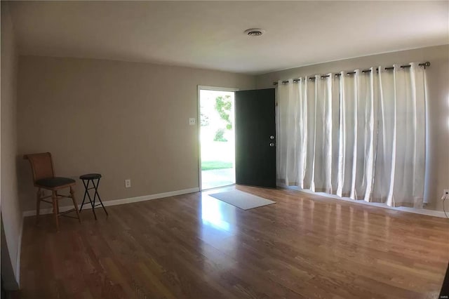 empty room featuring visible vents, dark wood finished floors, and baseboards